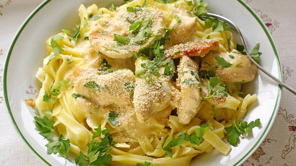 A plate of garlic Parmesan chicken pasta, featuring tender chicken pieces, creamy garlic Parmesan sauce, and al dente pasta, garnished with fresh herbs and grated cheese.