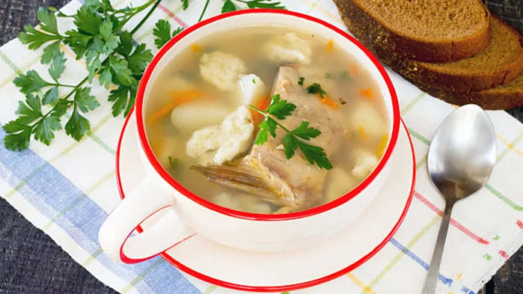 Soup of poulet made with leftover poulet rôti, served in a bowl with fresh herbs and vegetables.