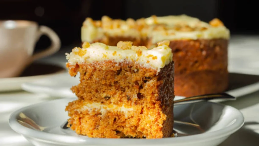 A rich Pumpkin Pie Cake layered with spiced pumpkin filling, cream frosting, and topped with crunchy crumbles, served on a rustic plate