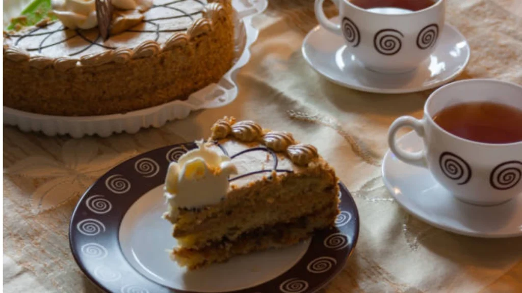 A slice of Milk Bar Pumpkin Pie Cake served on a plate with a cup of coffee, perfect for a sweet and indulgent breakfast.