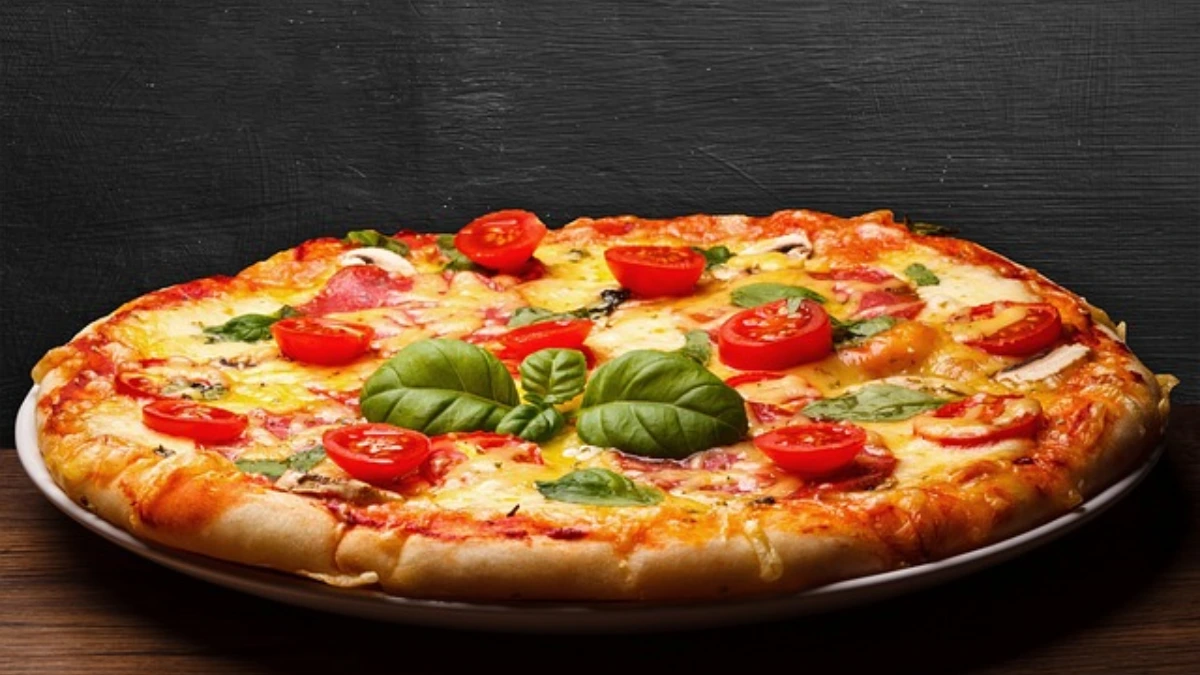 A close-up of a pizza with a golden, crispy crust, topped with melted cheese and fresh ingredients."